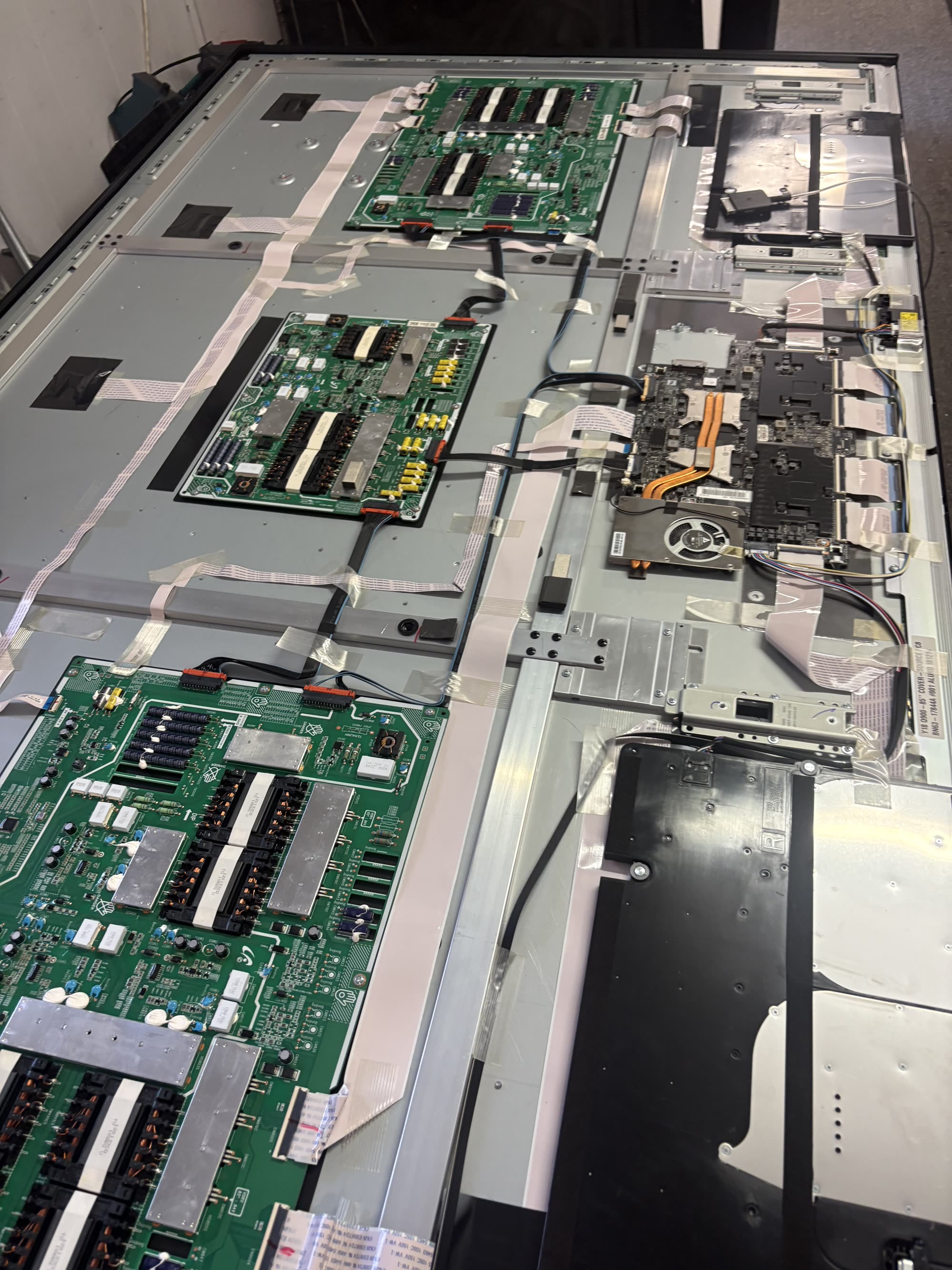 Two TV panels open on the repair bench with boards exposed